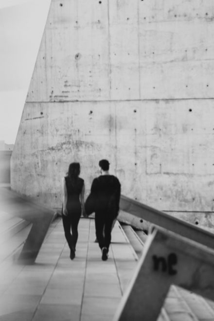 Black and white photograph of a couple walking away from the camera in an urban environment.