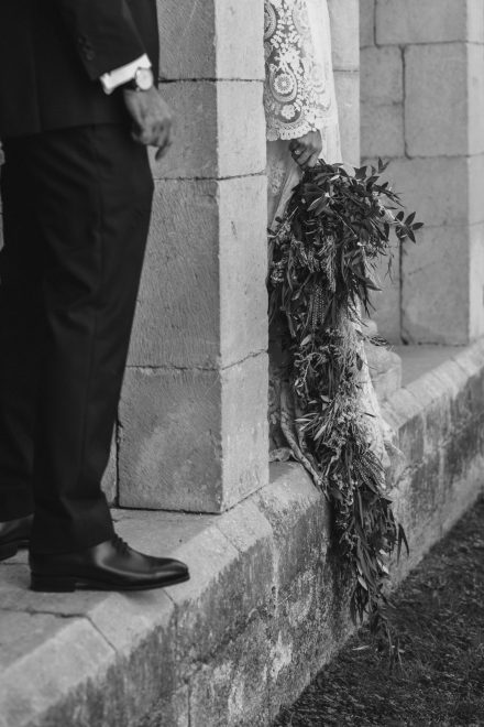 Artistic black and white photograph of the bride and groom separated by a column.