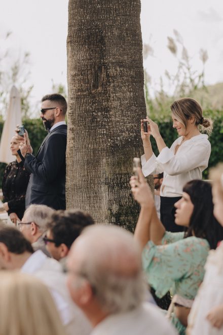 Image of the wedding guests filming and photographing the event from afar.