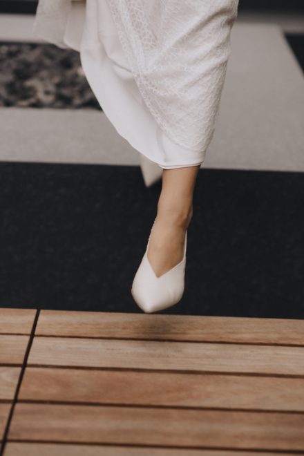 Close-up photograph of the bride walking in her white dress and heels.