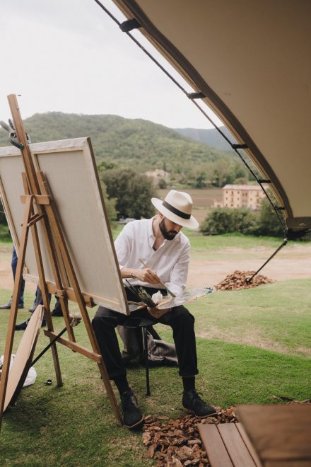 Photograph of a man with a bohemian style painting a picture during the wedding.