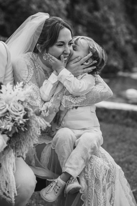 Black and white photograph of bride being kissed by a child