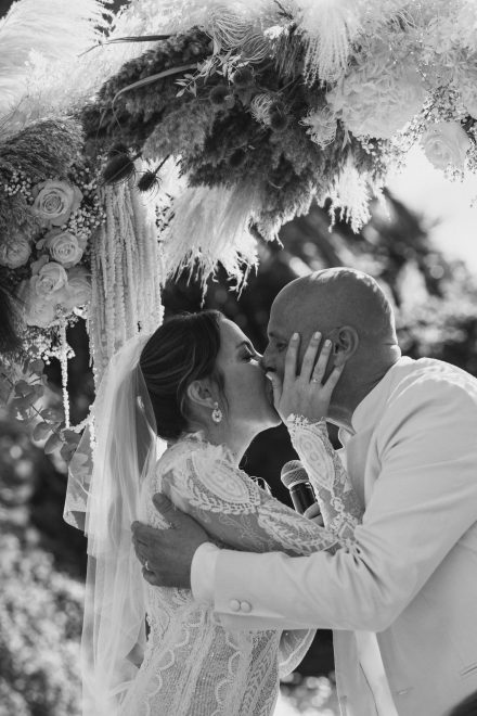 Black and white photograph of the bride and groom kissing at the altar.