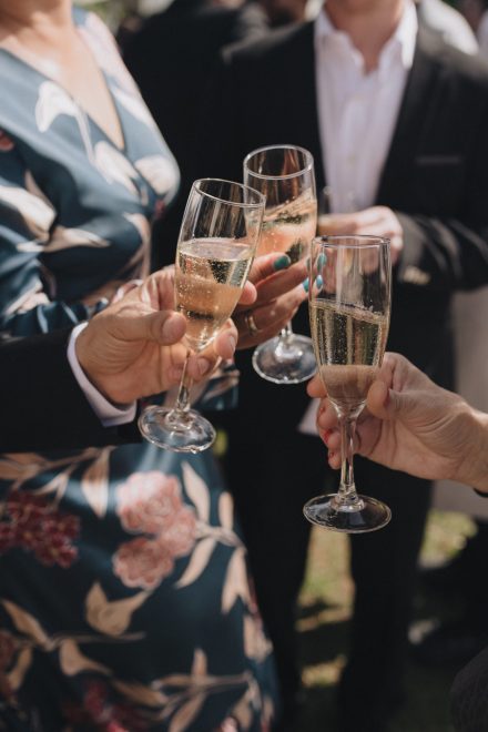 Close-up photograph of three people toasting with champagne glasses.