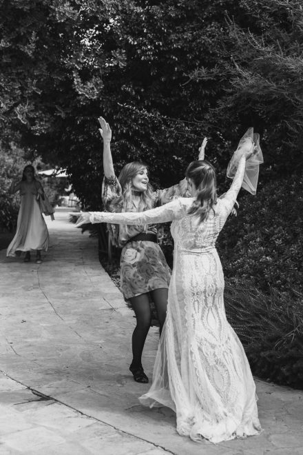 Photograph of a woman going to embrace the bride with great effusiveness.