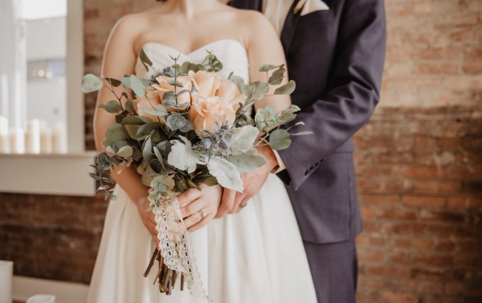 Photo of an embracing couple holding a bouquet of flowers.