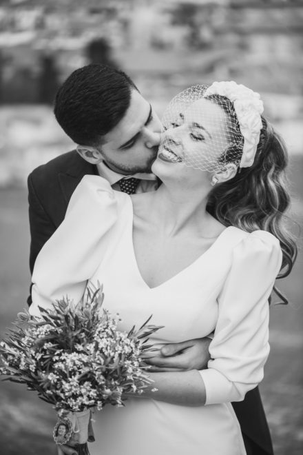 Couple of groom kissing bride while embracing her