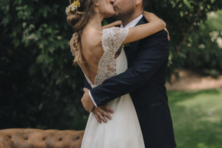 Photograph of the bride and groom embracing and kissing romantically.