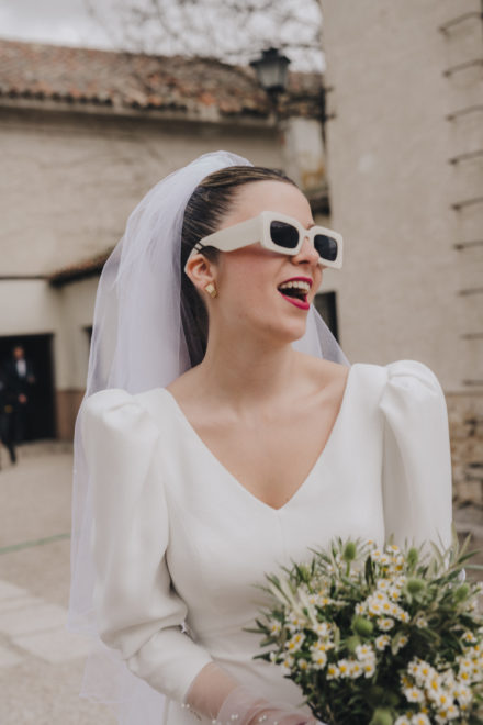 Image of the smiling bride with sunglasses to match the dress.