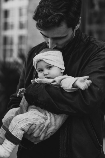 Black and white photograph of a father holding his son while kissing his head.